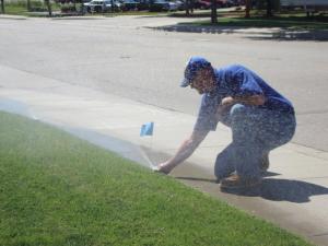 a Carmichael Sprinkler Repair tech adjusts a pop up head